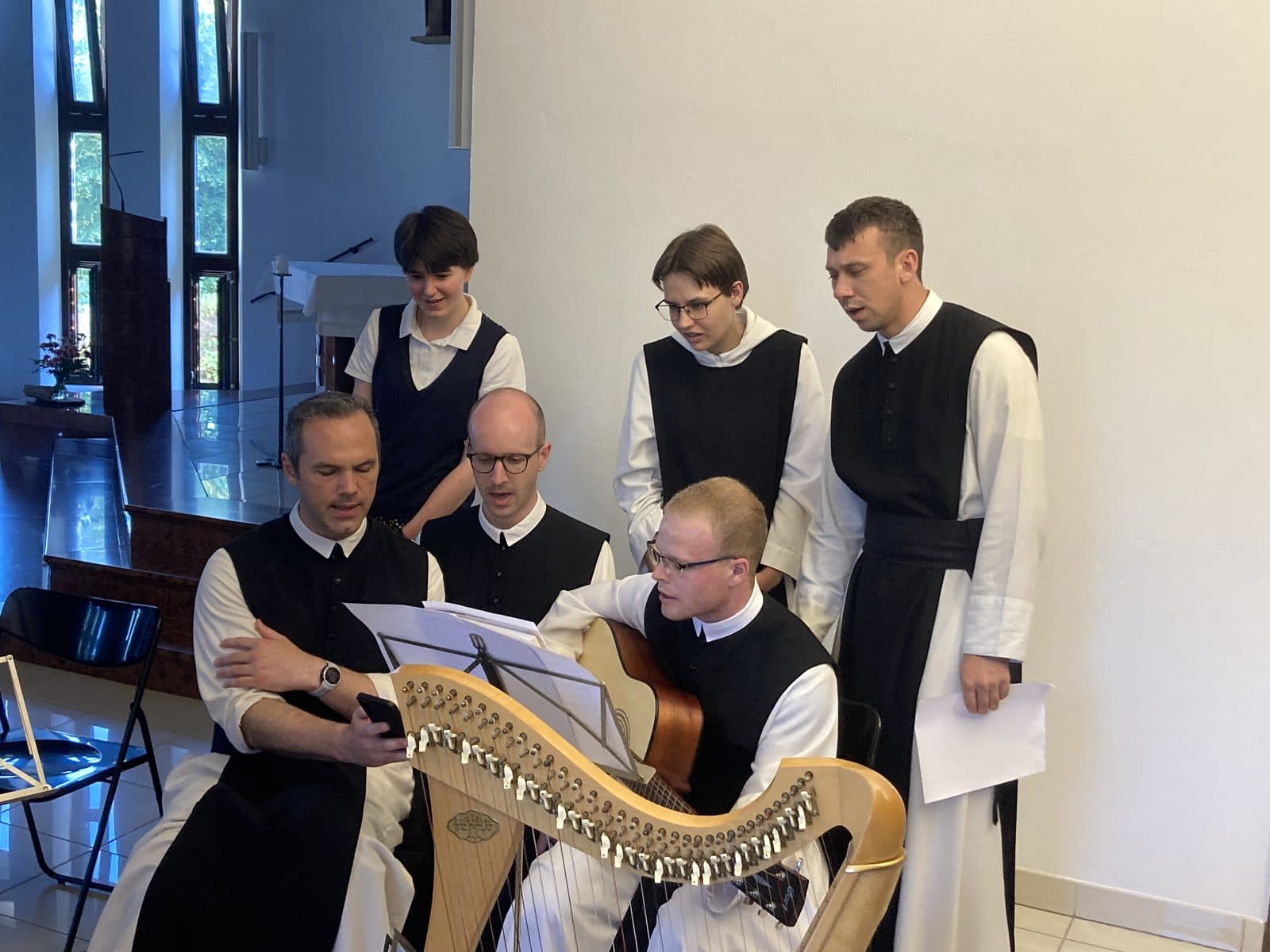 Ciszterci szerzetesek közösen énekelnek hárfa és gitár kíséretével